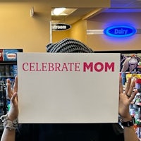 a woman holding up a sign that says celebrate mom
