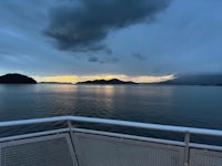 a view from the deck of a ferry as the sun sets over a body of water