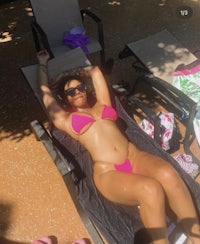 a woman in a pink bikini laying on a lounge chair