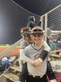 two softball players hugging each other on the field