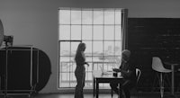 a man and woman sitting at a table in front of a window