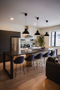 a kitchen with a black island and chairs