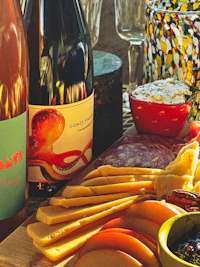 a platter of cheese, crackers and wine on a table