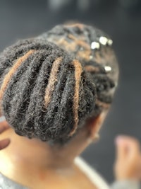 a woman with dreadlocks is getting her hair braided
