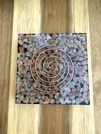 a spiral made of copper and stones on top of a wooden table