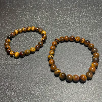 two tiger eye bracelets on a black surface