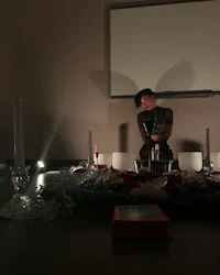 a woman sits at a table in front of a projection screen
