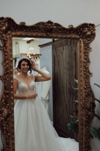 a bride in a wedding dress standing in front of a mirror