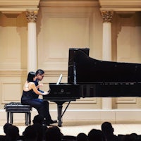 two people playing a piano in front of an audience