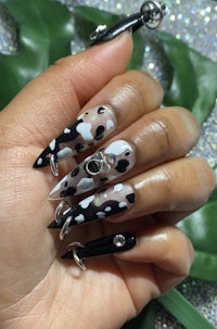 a woman holding a pair of black and white leopard print nails