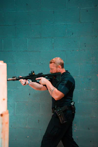 a man holding a gun in front of a blue wall