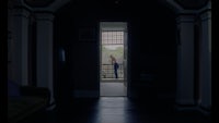 a woman is standing in an open doorway in a dark room