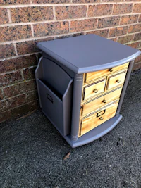 a grey nightstand with drawers in front of a brick wall