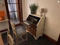 a desk with a laptop and a chair in a small room