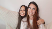 two girls are posing for a selfie on a bed
