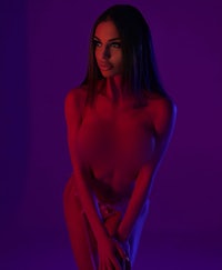 a woman in a bikini posing in front of a purple light