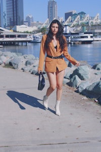a woman wearing a tan blazer and white shorts