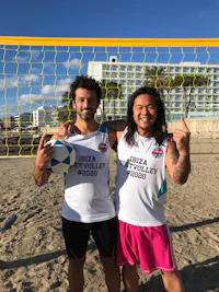 two people posing in front of a volleyball net