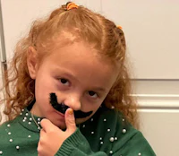 a little girl with a mustache on her finger