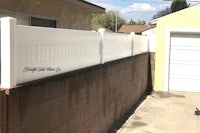 a white fence in a backyard with a sign on it
