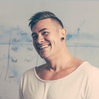 a man smiling in front of a white wall