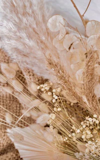 a bouquet of dried flowers and grasses on a bed