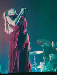 a woman in a red dress singing into a microphone