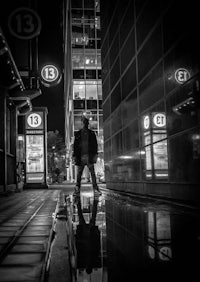 a black and white photo of a man standing in a puddle