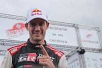 a man in a red bull rally shirt giving the thumbs up