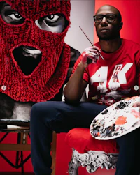 a man with a red mask sitting in front of a painting