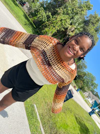 a young woman wearing a crocheted sweater and shorts