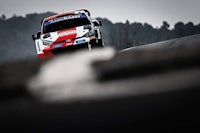a red and white rally car driving down a road