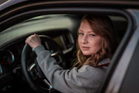 a young woman sitting in the driver's seat of a car