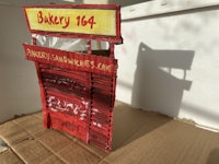 a cardboard model of a bakery with a sign on it