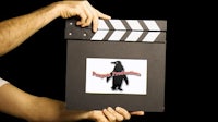 a person holding a movie clapboard with a penguin on it