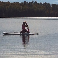 a woman practicing yoga on a paddle board in a lake