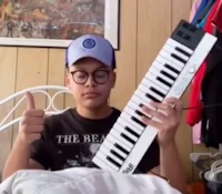 a young man holding a keyboard and giving thumbs up