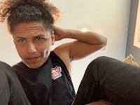 a man with curly hair sitting on a bed