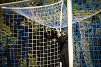 a man in a black mask is standing in a soccer net