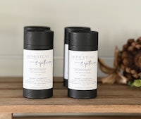 three bottles of deodorant sitting on a wooden table