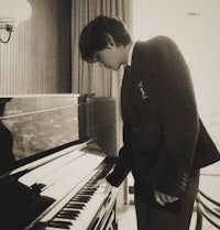 a young man in a suit playing a piano