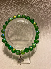 a green bead bracelet with a silver charm