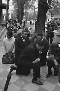 luther king jr kneeling in front of a crowd of people