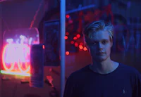 a young man standing in front of a neon sign