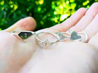 a hand holding a pair of silver rings with initials on them