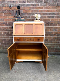 an old wooden desk with drawers and a clock on it