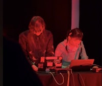 two people sitting at a table with laptops in front of them