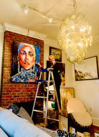 a woman is working on a painting in a living room