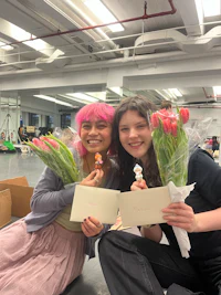 two women with pink hair holding bouquets of flowers