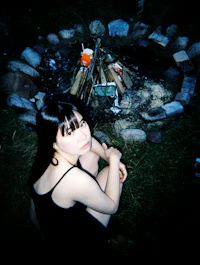 a woman sitting in front of a fire pit